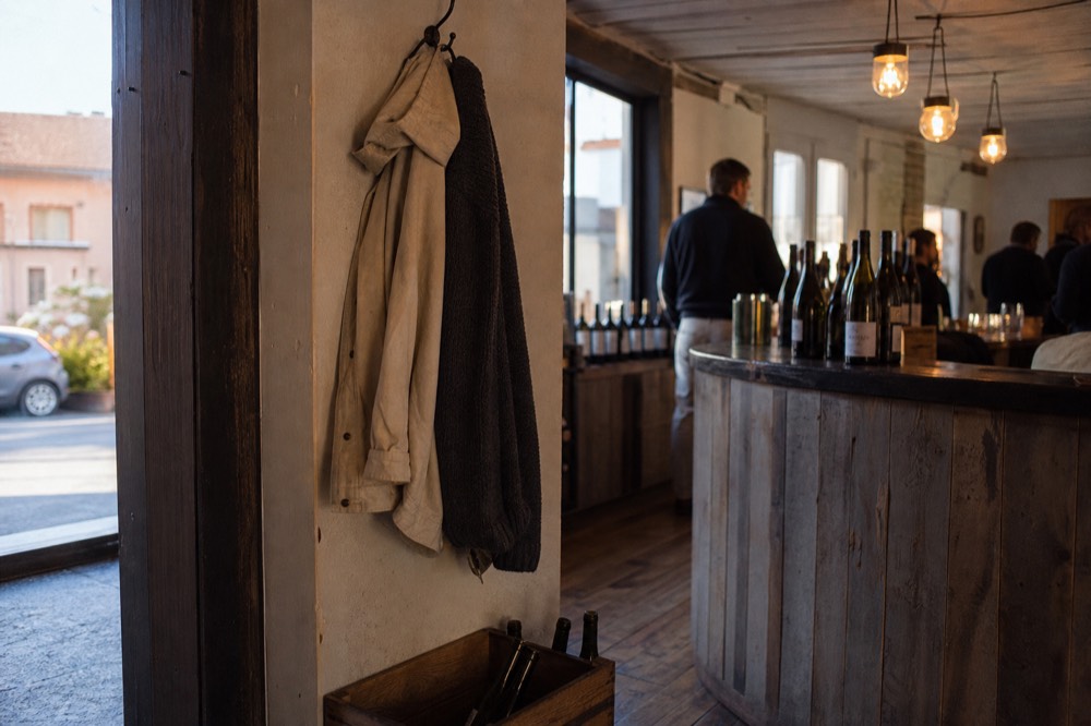 Dark casual clothing and a light jacket hanging near a winery tasting bar