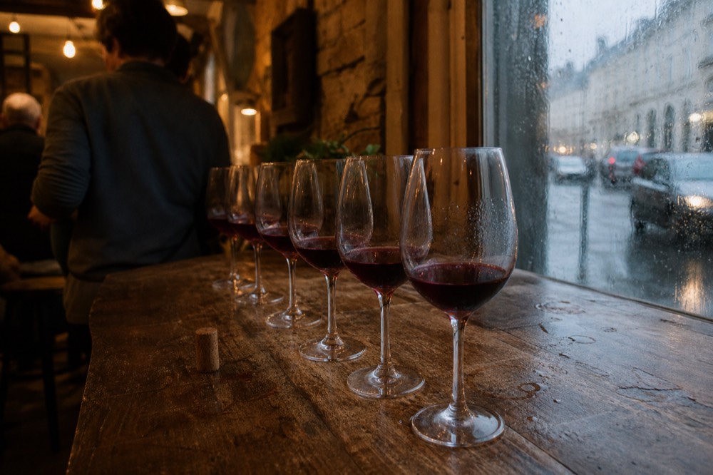 A tasting flight of red wine glasses arranged on a wooden tasting room counter