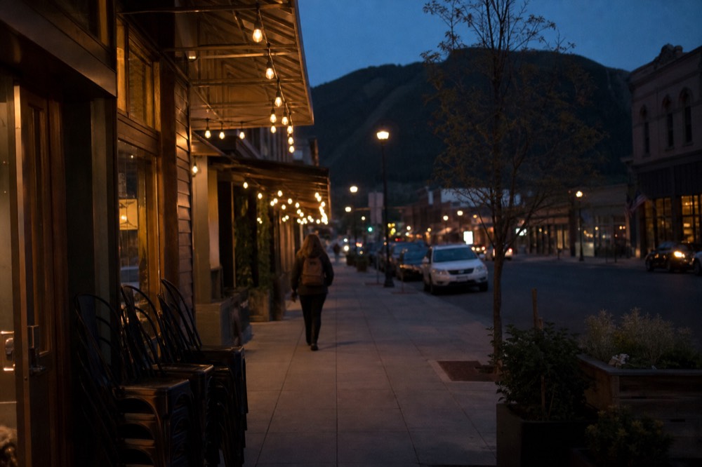 Small-town main street at dusk with hills in the distance