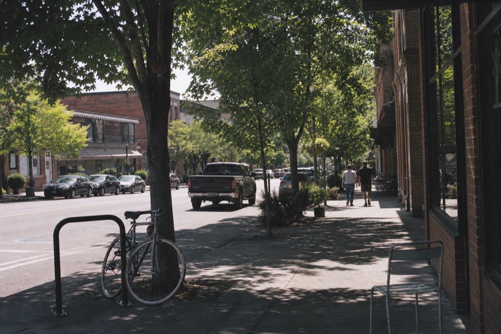 A tree-lined small-town street with brick storefronts in McMinnville